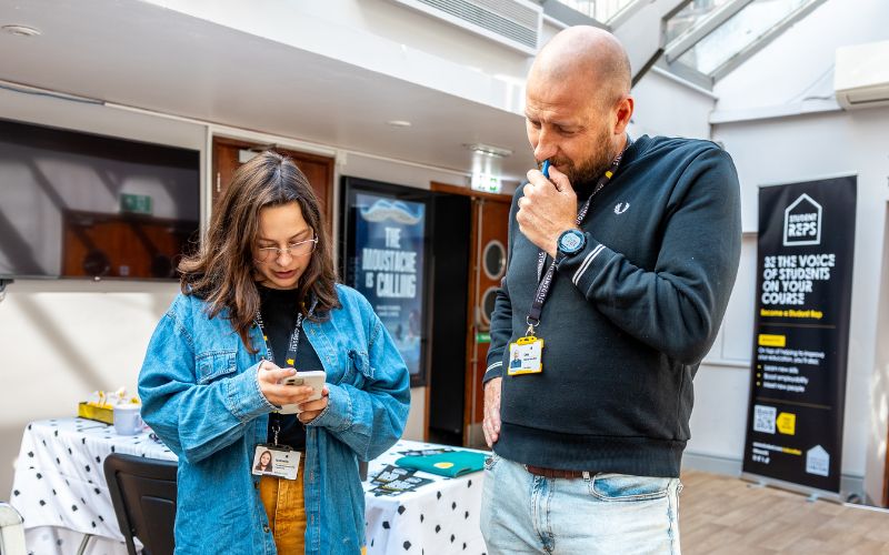 two staff members looking at phone
