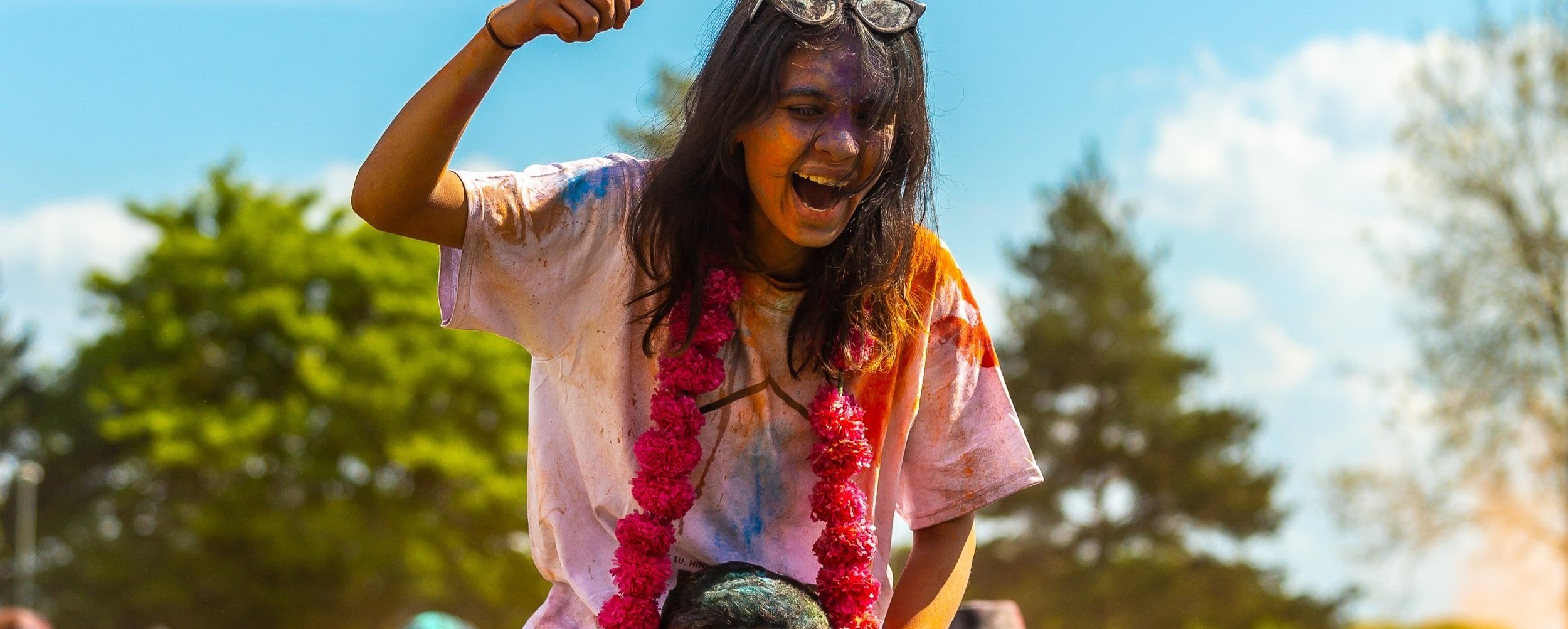 Essex student covered in paint on someones shoulders at Holi